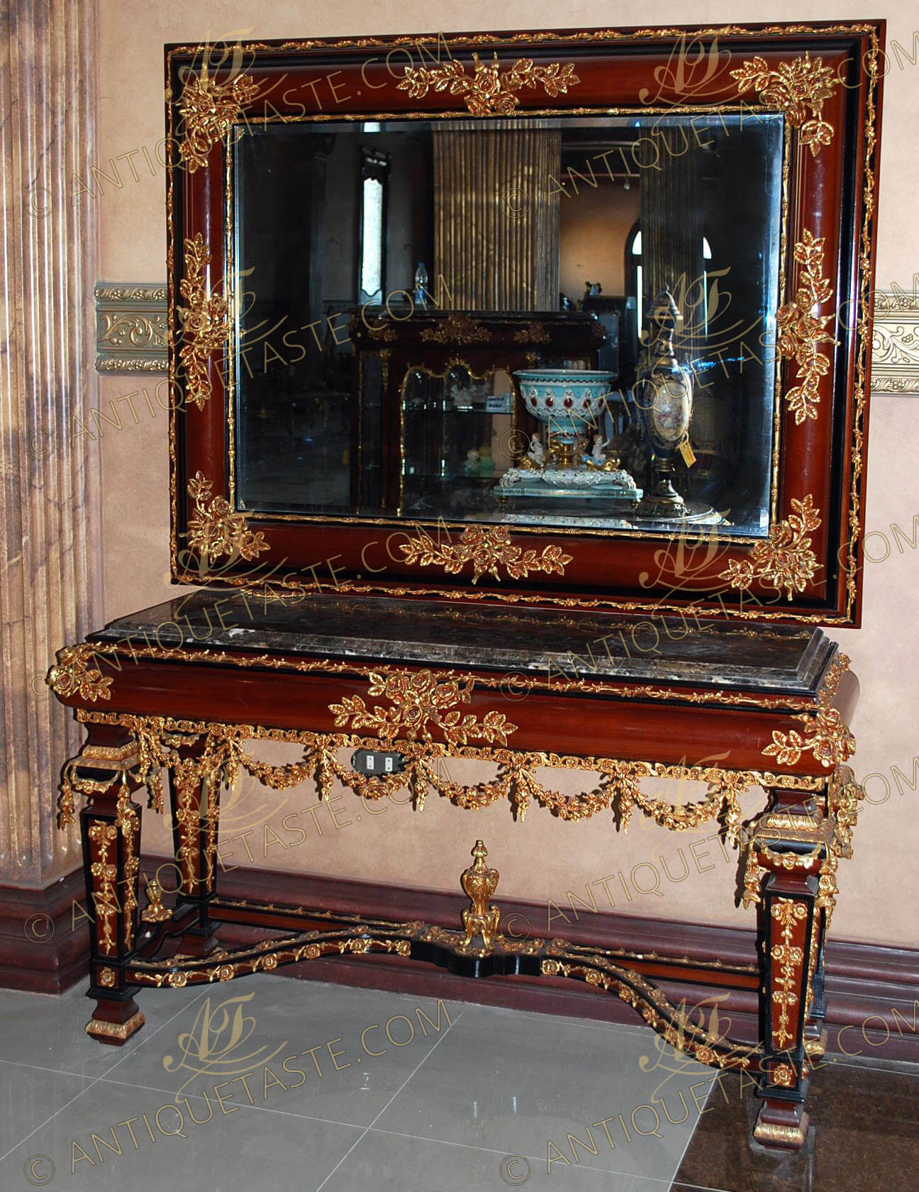 A stately and imposing Louis XIV Neoclassical style gilt-ormolu-mounted mahogany finish console table with a matching mirror, full of ormolu garlands, swags, strap-works, scrolled leaf motifs, trellis, pierced works. The console with wrap around ormolu sabots and top ormolu foliate mount joined by an ormolu filet. The ormolu filet continues all around the contours of the mirror and the table. The mirror frame is ornamented with ormolu flower bouquets with leafy branches. The molded beveled  marble top console table raised on robust square tapered legs, with a convex apron ornamented with gilt leafy ormolu works of flower bouquets and branches. The legs and the frieze are ornamented with ormolu pendant swags and connected with curvy X stretcher garnished with flower garlands. The underneath sides and center are adorned with ormolu urn of prosperity